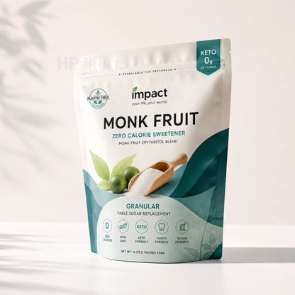 A sealed mylar bag of Impact Keto Monk Fruit Zero Calorie Sweetener, featuring a white and teal design with illustrations of green monk fruit and a wooden scoop of powder, set against a light background with soft leaf shadows.