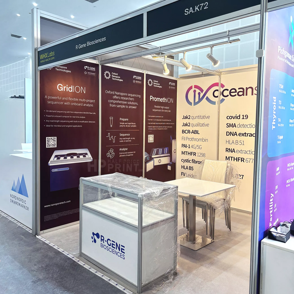 A side view shell scheme booth display for R Gene Biosciences and IQ Oceans at a medical or scientific conference, featuring branded panels, a sample storage cabinet, and a small glass display case on a table.