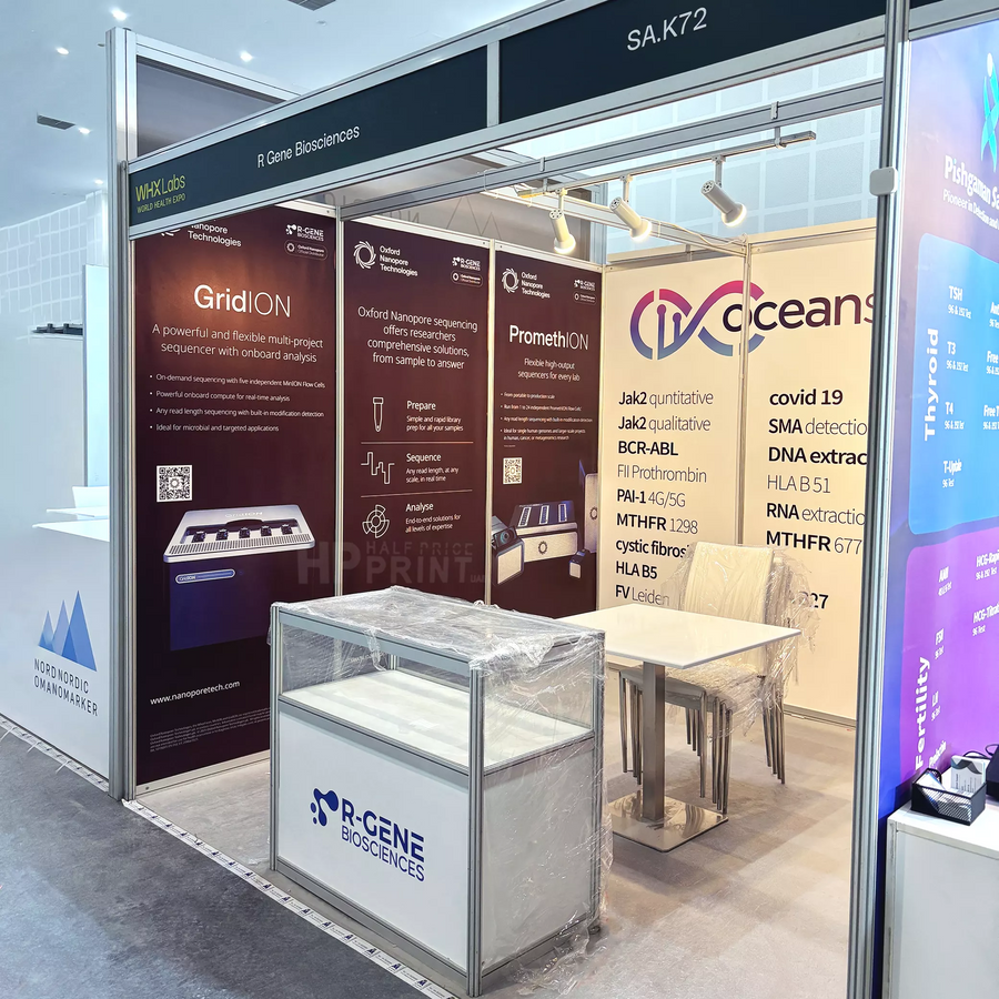A side view shell scheme booth display for R Gene Biosciences and IQ Oceans at a medical or scientific conference, featuring branded panels, a sample storage cabinet, and a small glass display case on a table.