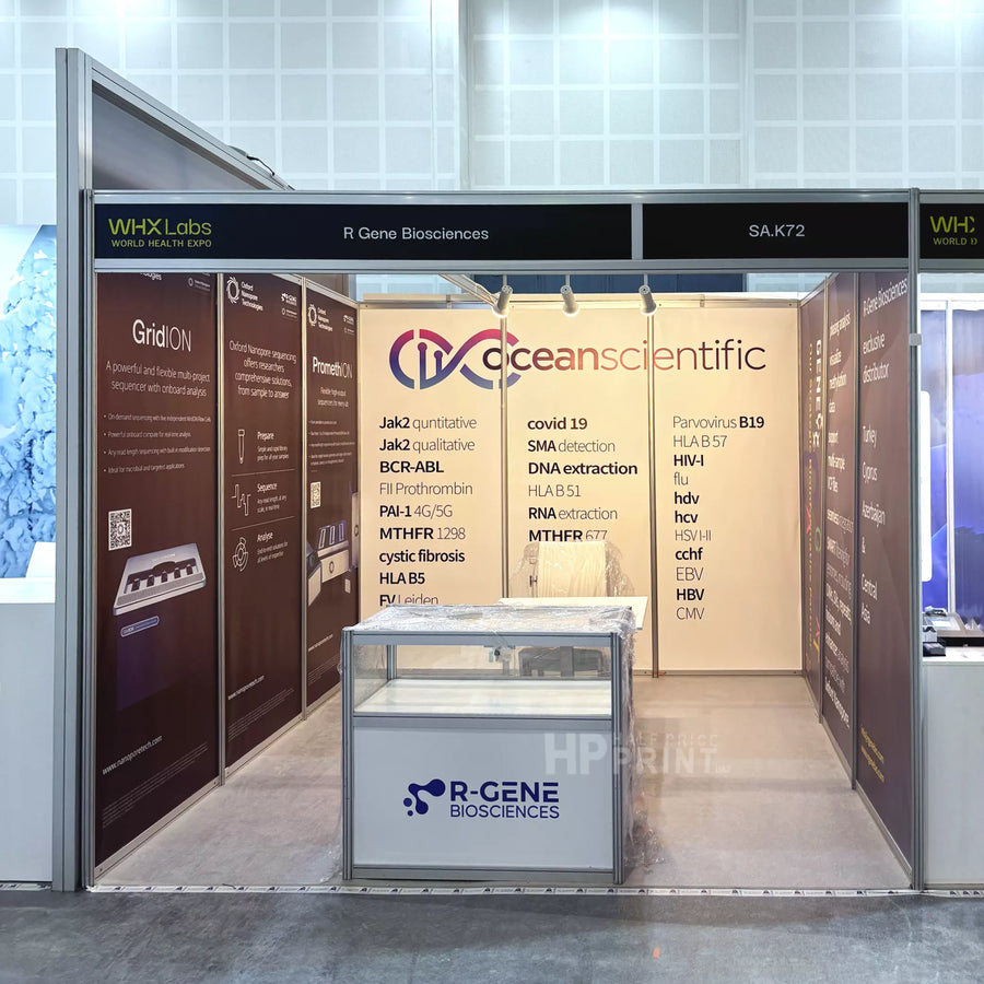 A shell scheme booth display for R-GENE Biosciences and Oceanscientific, featuring a central glass display case with the R-GENE logo, brown and beige informational panels, and a black header sign.