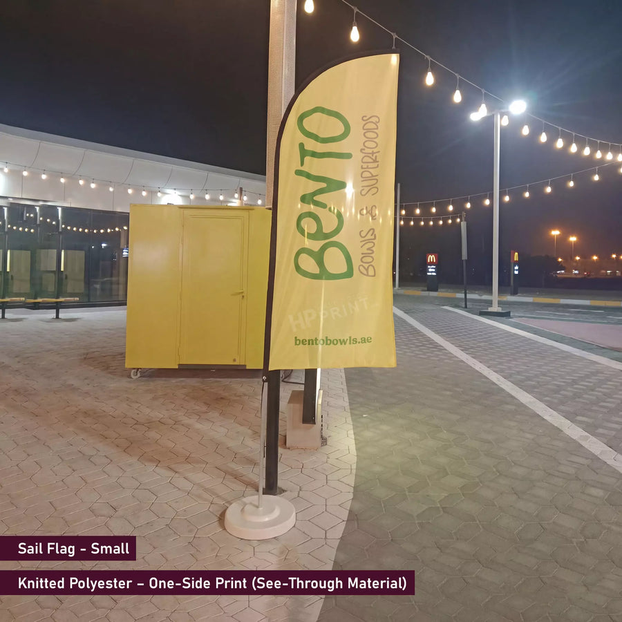 Yellow sail flag with 'Bento' branding on a pole at night.