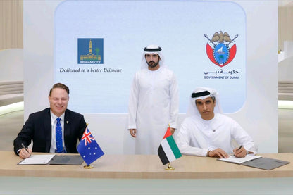 Three men at a table with flags of Australia and Dubai, behind them are two organizations' logos.