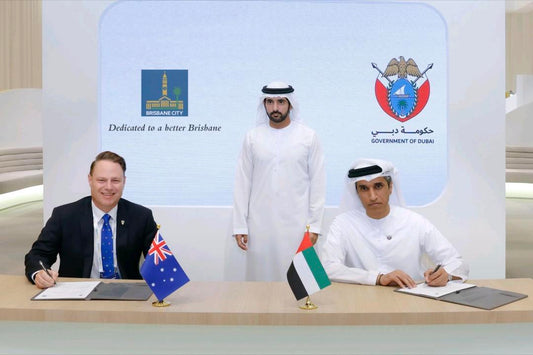 Three men at a table with flags of Australia and Dubai, behind them are two organizations' logos.