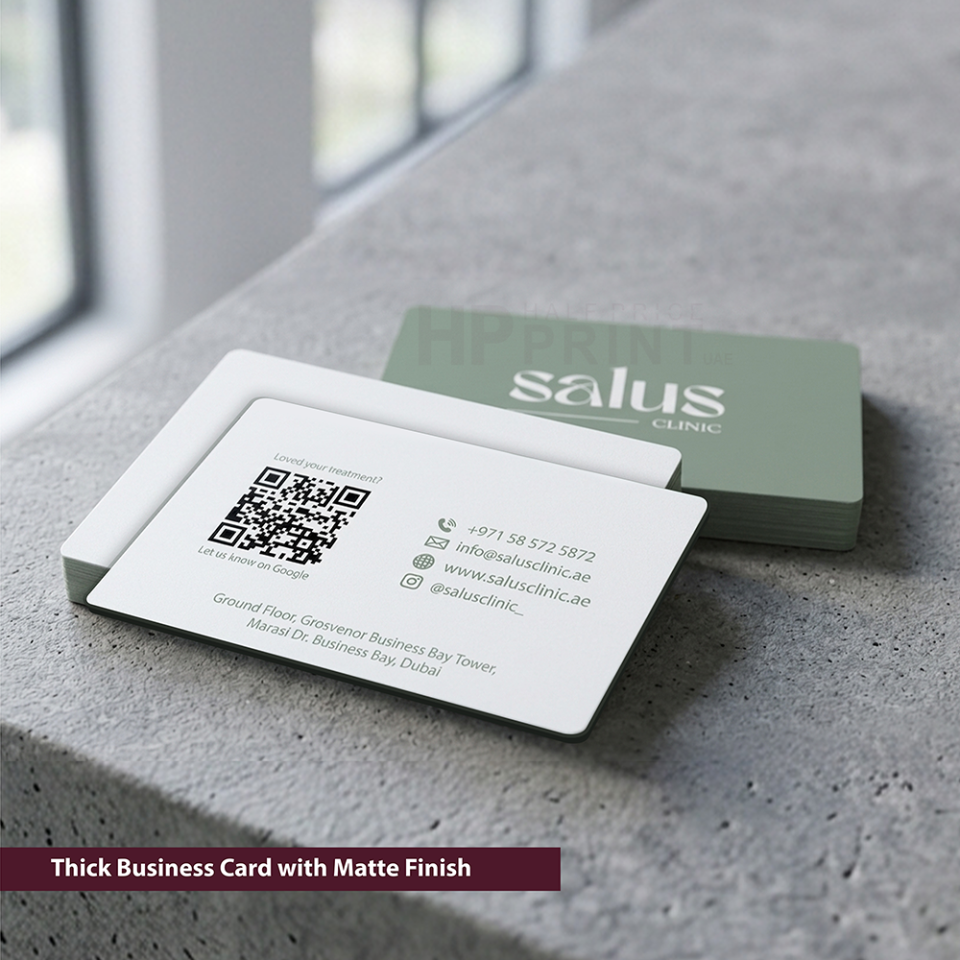 Two business cards with 'salus clinic' branding on a concrete surface.