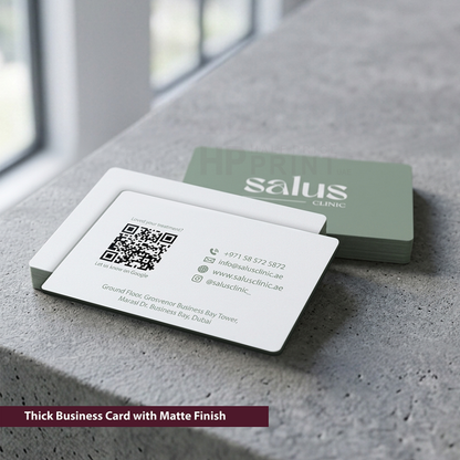 Two business cards with 'salus clinic' branding on a concrete surface.
