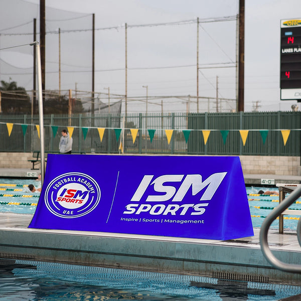Blue sports event banner with logos and text at a poolside.