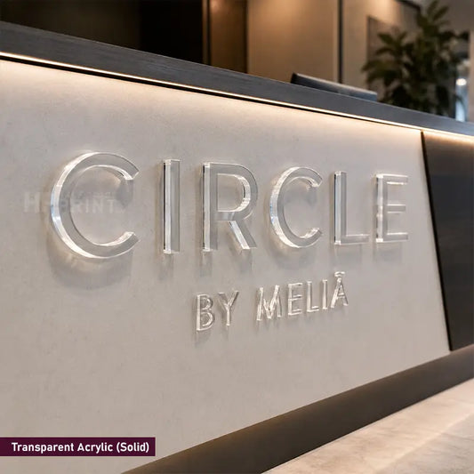 Transparent acrylic 3D lettering on a modern reception desk, featuring the brand name 'CIRCLE BY MELIÁ'. The letters are backlit to give them a glowing, metallic look against a light beige stone surface.