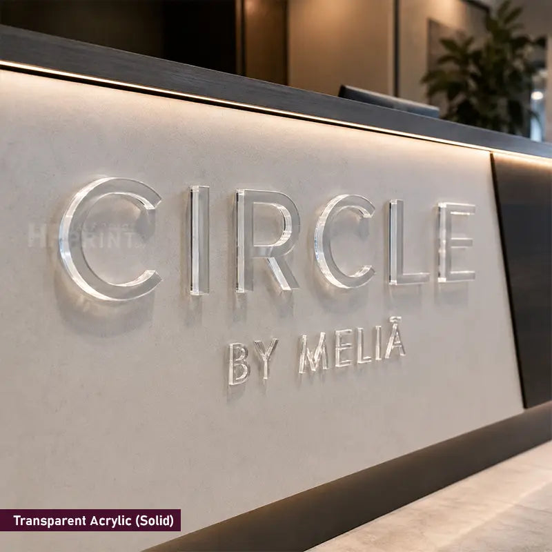 Transparent acrylic 3D lettering on a modern reception desk, featuring the brand name 'CIRCLE BY MELIÁ'. The letters are backlit to give them a glowing, metallic look against a light beige stone surface.