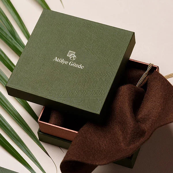 Luxury green two-piece gift box with brown fabric insert and gold necklace, packaging design