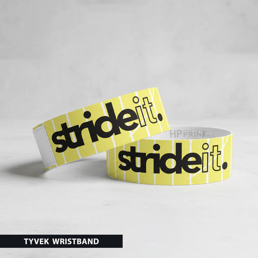 Yellow tyvek wristband with 'stride it.' text on a gray background