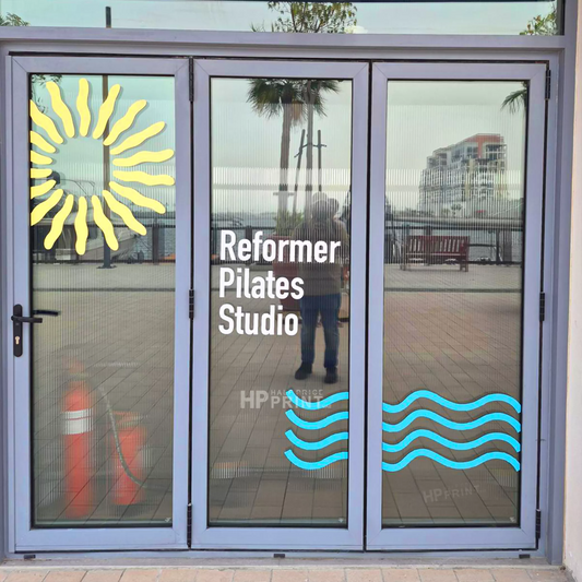 Glass door with 'Reformer Pilates Studio' window branding and decorative elements.