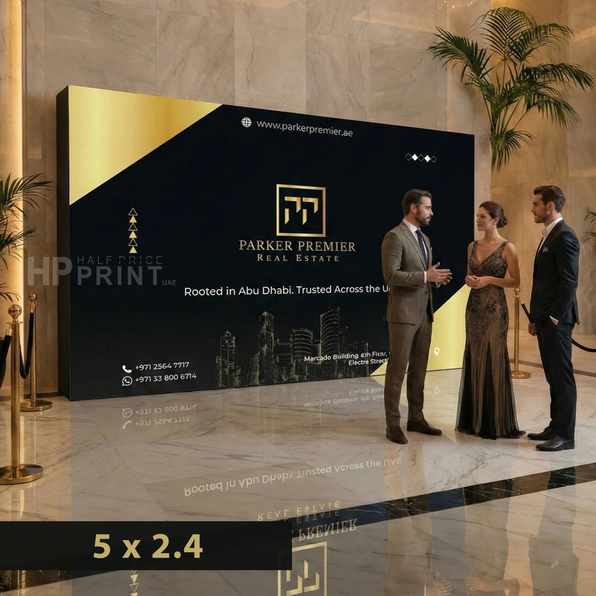 Two men and a woman standing in front of a large wooden backdrop displaying Parker Premier Real Estate in a luxurious lobby.